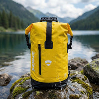 RIXVA 35L yellow waterproof PVC backpack with roll-top closure and front zipper pocket on a wet rock by a lake.